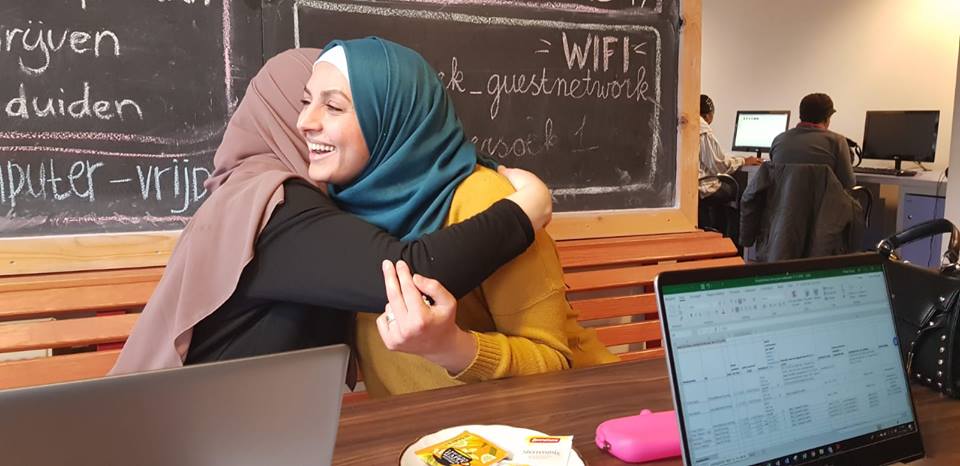 Vrouwen knuffelen elkaar in les digitale vaardigheid