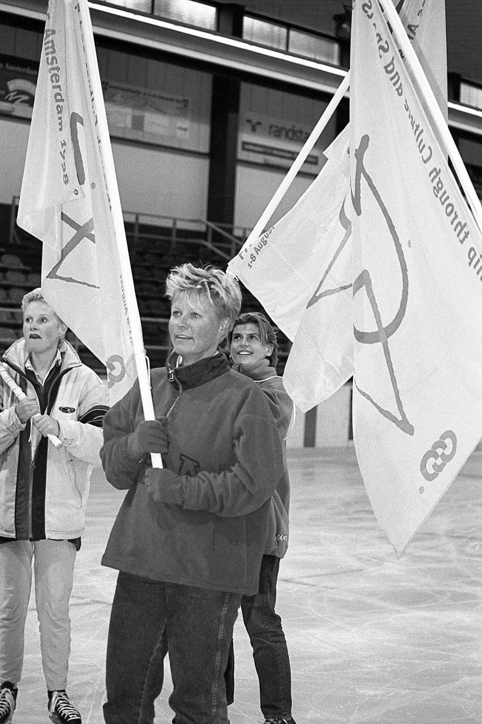 Zwart-witfoto van Niek van der Spek met een Gay Games-vlag in haar handen