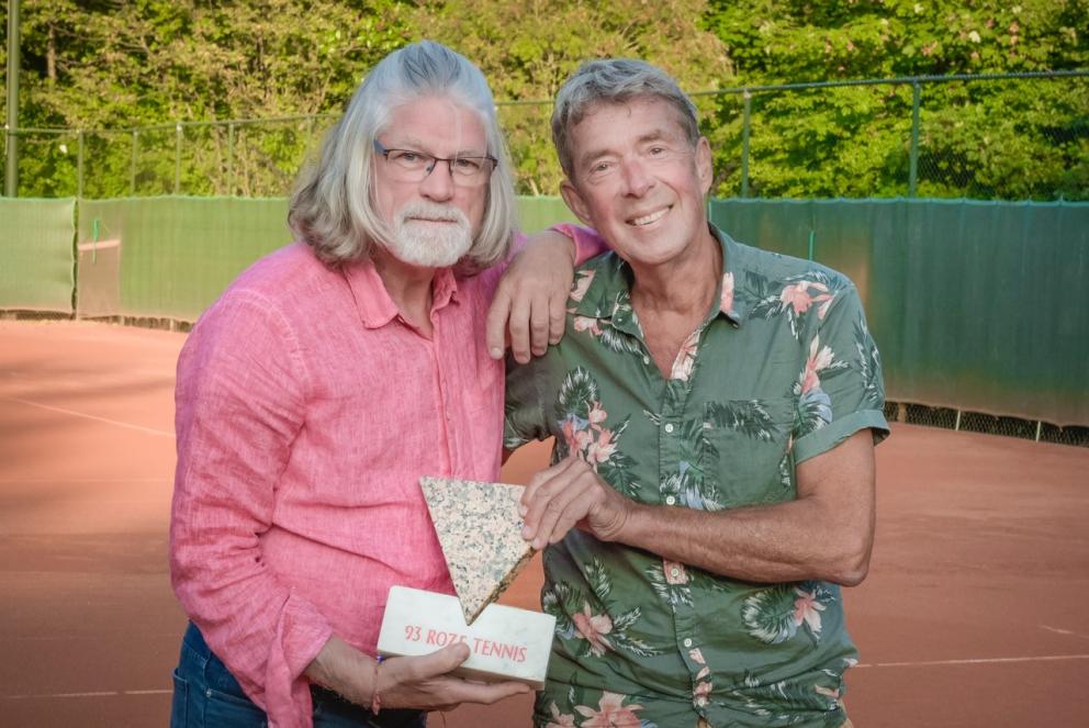 Tom en Ed op de tennisbaan met een beeldje van een driehoek vast, waarop staat: 93 roze tennis