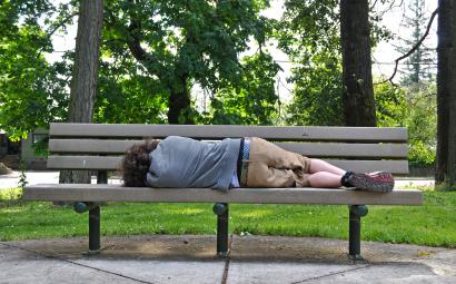 een dakloos persoon slapend op een bank in het park