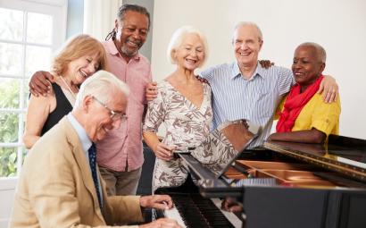 Groep ouderen zingt rondom een piano