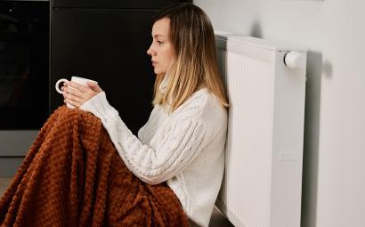 Vrouw zit tegen verwarming in koud huis