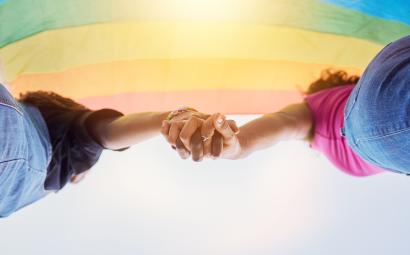 Twee vrouwen hand in hand met regenboogvlag