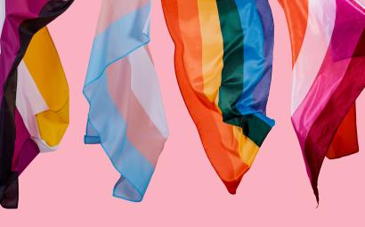 Roze achtergrond met diverse Pride-vlaggen: non-binair, transgender, bi en regenboog