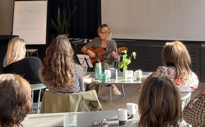 Maryse den Hollander speelt gitaar en zingt tijdens de bijeenkomst.
