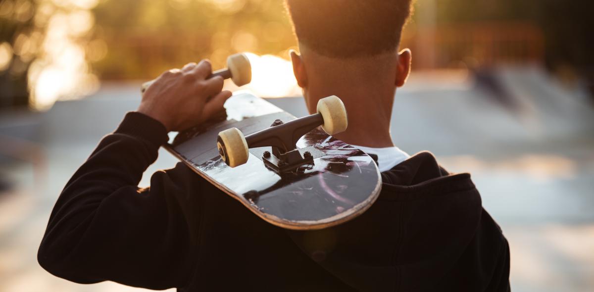 Jongen met skateboard van achterkant