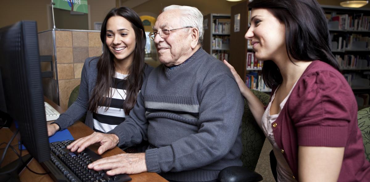 Twee vrouwen en een oudere man met een computer