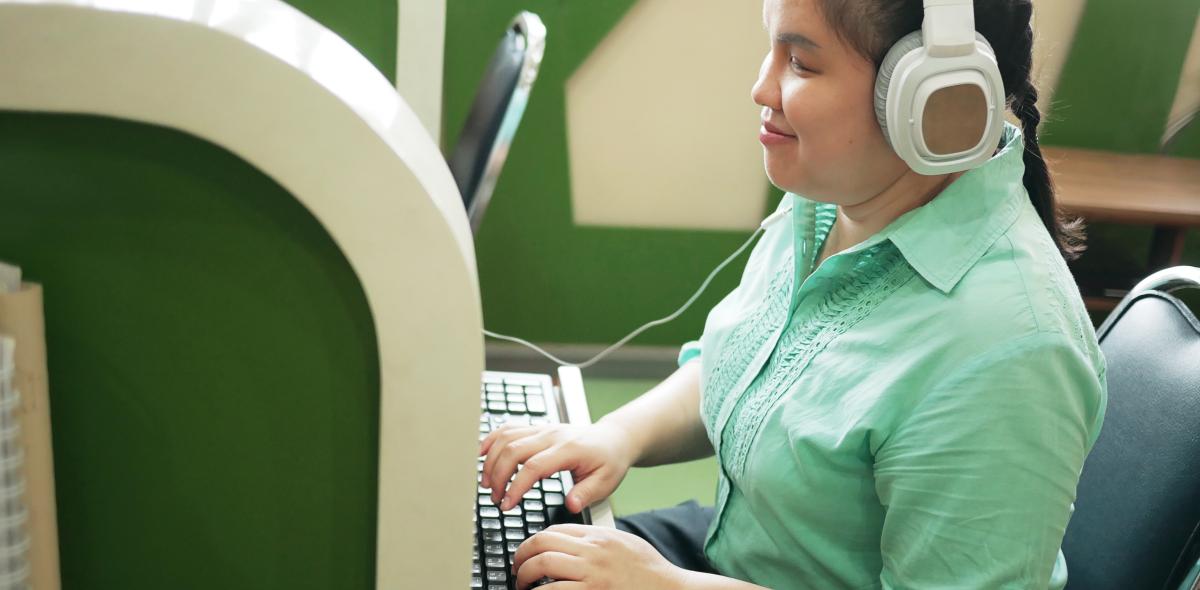 Blind meisje op de computer aan het werk met koptelefoon op